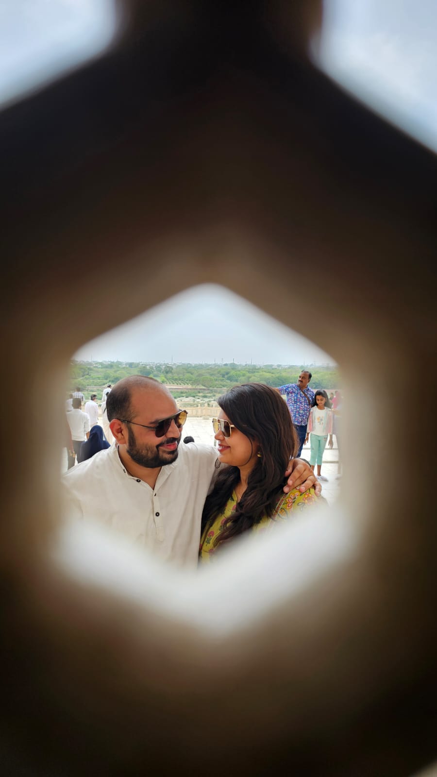 Neha and Deepak smiling at each other through a stone opening